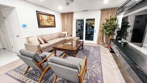 A living room with a sofa, two armchairs, a coffee table, a TV, and a painting on the wall. - Spacious 4-bedroom house in enchanting Coachella with AC (Coachella)