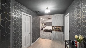 A hallway leading to a bedroom with a bed, a ceiling fan, and a wall-mounted TV. - Spacious 4-bedroom house in enchanting Coachella with AC (Coachella)
