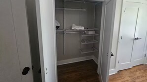 A walk-in closet with metal shelving, a white door, and a wooden floor. - 10 mins from Mercedes Benz stadium! (Atlanta)