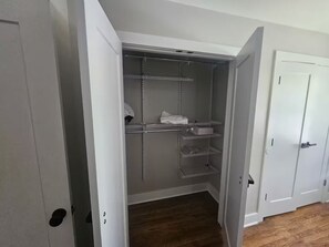 Ein begehbarer Kleiderschrank mit Metallregalen, einer weißen Tür und einem Holzboden.