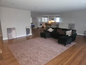 Ein großzügiger Wohnbereich mit einem großen, schwarzen Ecksofa, einem pinken Teppich und Holzböden.