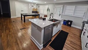 A modern kitchen with a central island, built-in appliances, and a dining area with a pool table. - 10 mins from Mercedes Benz stadium! (Atlanta)