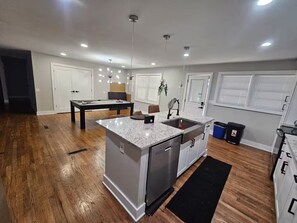 A modern kitchen with a central island, built-in appliances, and a dining area with a pool table.