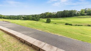 A paved road with a grassy area and trees in the background. - THO2-2, Moose Creek 2BR Condo with Golf Views at Thousand Hills (Branson)