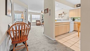 A hallway leading to a dining area with a wooden chair, a fireplace, and a kitchen with wooden cabinets and a tiled backsplash. - THO2-2, Moose Creek 2BR Condo with Golf Views at Thousand Hills (Branson)