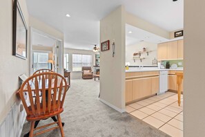 A hallway leading to a dining area with a wooden chair, a fireplace, and a kitchen with wooden cabinets and a tiled backsplash. - THO2-2, Moose Creek 2BR Condo with Golf Views at Thousand Hills (Branson)