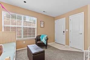 A room with a bed, a chair, a bench, a window with blinds, a door, and a wall-mounted picture. - THO2-2, Moose Creek 2BR Condo with Golf Views at Thousand Hills (Branson)