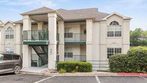 A multi-story apartment building with a central staircase, balconies, and a parking area. - THO2-2, Moose Creek 2BR Condo with Golf Views at Thousand Hills (Branson)