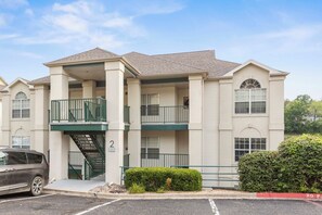 A multi-story apartment building with a central staircase, balconies, and a parking area. - THO2-2, Moose Creek 2BR Condo with Golf Views at Thousand Hills (Branson)