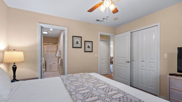 A hotel room with a bed, a ceiling fan, a shower, and a television. - THO2-2, Moose Creek 2BR Condo with Golf Views at Thousand Hills (Branson)