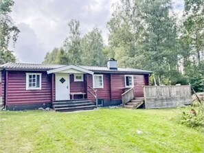 A small, single-story wooden house with a front porch and steps leading to the entrance. - Blockhaus mit Sauna direkt am See by Interhome (Virserum)