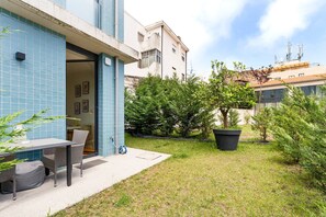 A courtyard with a table and chairs, a potted plant, and a building with blue tiles and a door. - GuestReady-Modern Retreat with Private Terrace (Porto)