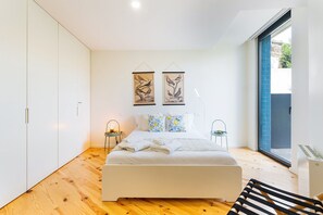 A modern bedroom with a bed, two wall-mounted artworks, a side table, and a chair. - GuestReady-Modern Retreat with Private Terrace (Porto)