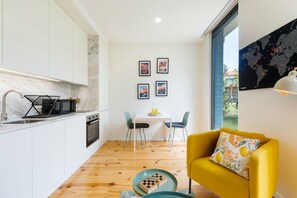 Un espace de vie compact comprenant une cuisine, un coin repas et un fauteuil jaune.