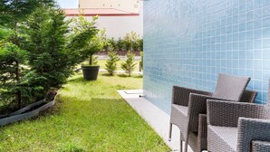 Ein Patio mit Gartenmöbeln, einer gefliesten Wand und einem Gebäude im Hintergrund.