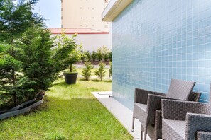 Ein Patio mit Gartenmöbeln, einer gefliesten Wand und einem Gebäude im Hintergrund.