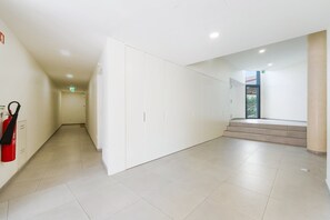 A clean, modern hallway with a fire extinguisher, a staircase, and a door leading to another room. - GuestReady-Modern Retreat with Private Terrace (Porto)