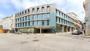 Ein modernes Gebäude mit einer gewölbten Fassade, großen Fenstern und einem überdachten Eingang.