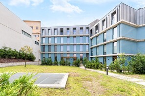 A modern building with a courtyard, featuring a central open space with a metal grate, surrounded by greenery and a pathway. - GuestReady-Modern Retreat with Private Terrace (Porto)
