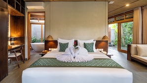Une chambre d’hôtel avec un grand lit, deux lampes de chevet, un bureau avec une lampe, une chaise et une vue sur la verdure.