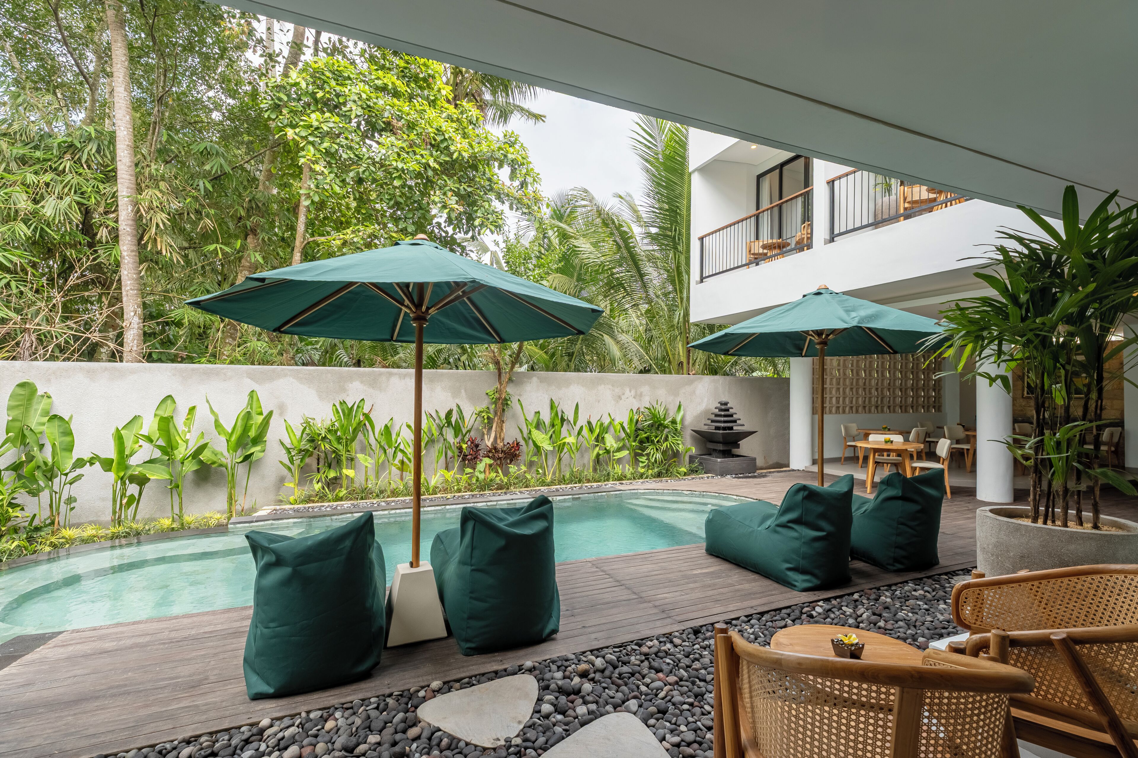 A poolside area with green umbrellas, seating, and a view of a modern building.