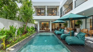 Un bâtiment moderne doté d’une piscine, d’un espace extérieur aménagé et d’une végétation luxuriante.