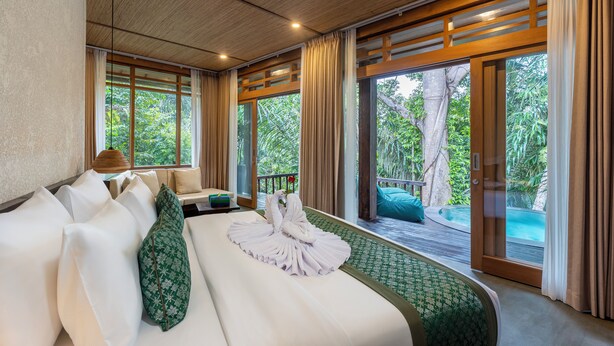 Une chambre avec un lit, un canapé, une vue sur la piscine et de grandes fenêtres.