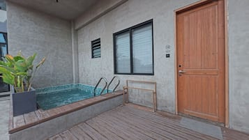 A spa area with a wooden deck, a pool, a wooden door, and a potted plant.