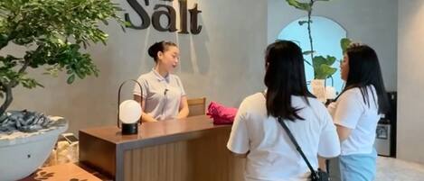 A reception desk with a sign reading 'The Salt,' a potted plant, and a small fountain.