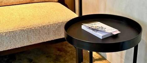 A round black table with a book on it, placed next to a sofa with a textured cushion.