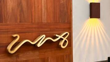 Pared de madera con una lámpara moderna y un letrero metálico decorativo.