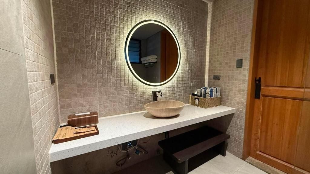 A bathroom with a round mirror, a sink, and a towel rack.