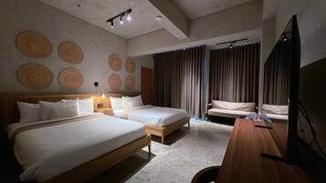 A hotel room with two beds, a desk, a TV, and a wall with circular patterns.