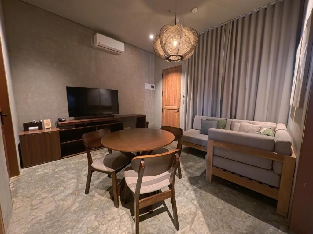 Una sala moderna con una mesa redonda de comedor, sillas, un sofá, un televisor y una lámpara colgante.