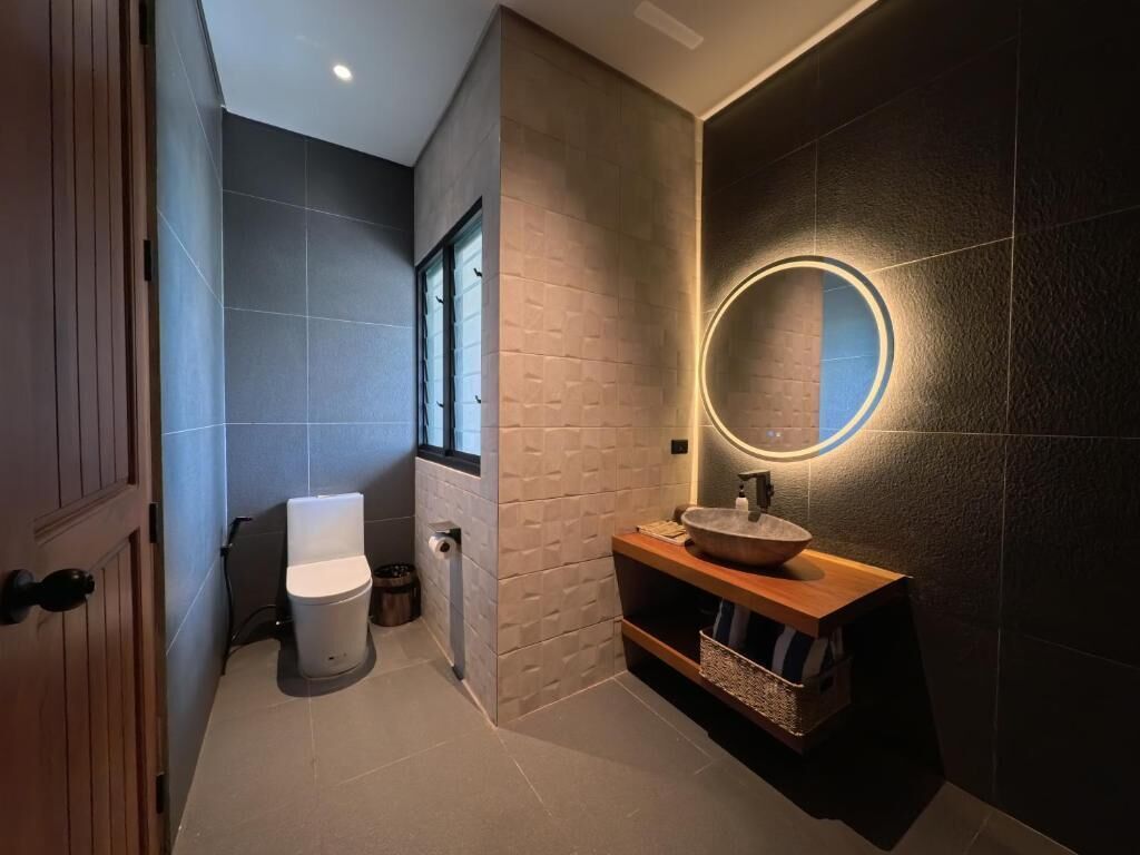 A modern bathroom with a toilet, sink, and mirror.