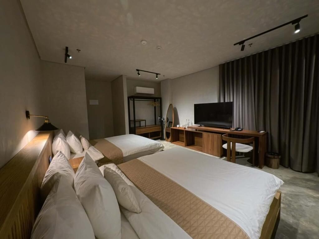 Hotellihuone, jossa on kaksi sänkyä, työpöytä, televisio ja vaatekaappi.