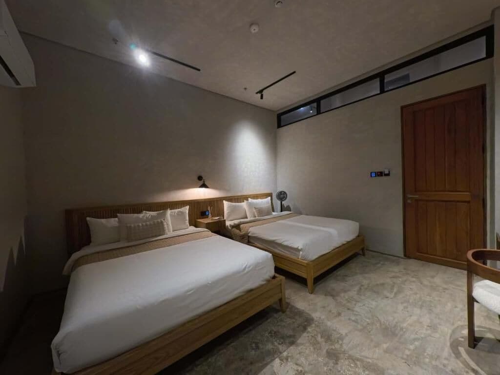 A bedroom with two beds, a wooden door, and a small table.