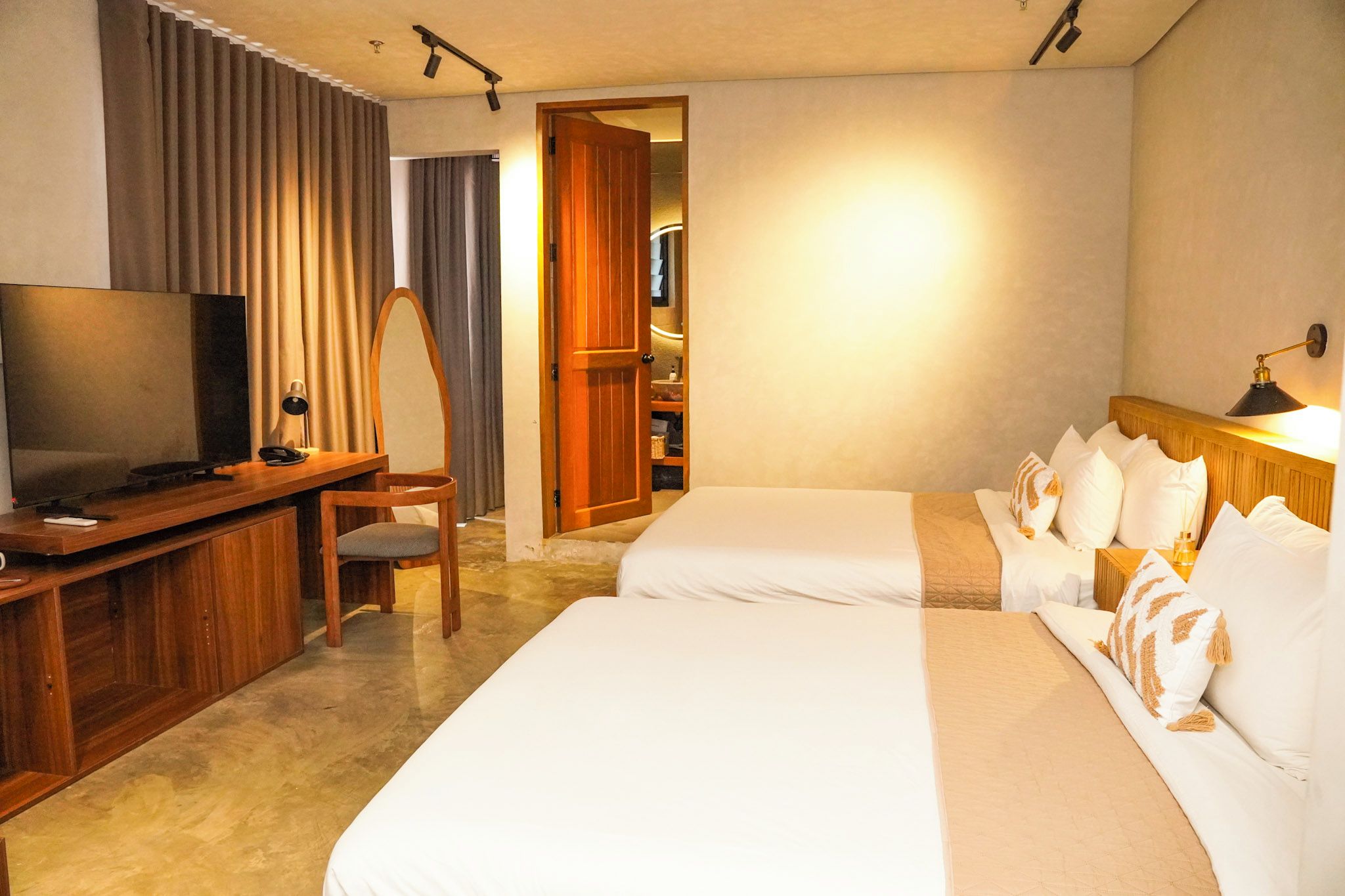 A hotel room with a TV, desk, chair, two beds, and a wardrobe.