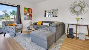 Uma sala de estar moderna com um sofá seccional, uma mesa de centro redonda e uma poltrona cinza.
