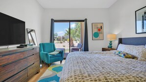 Quarto com cama, televisão, cadeira, escrivaninha e janela.