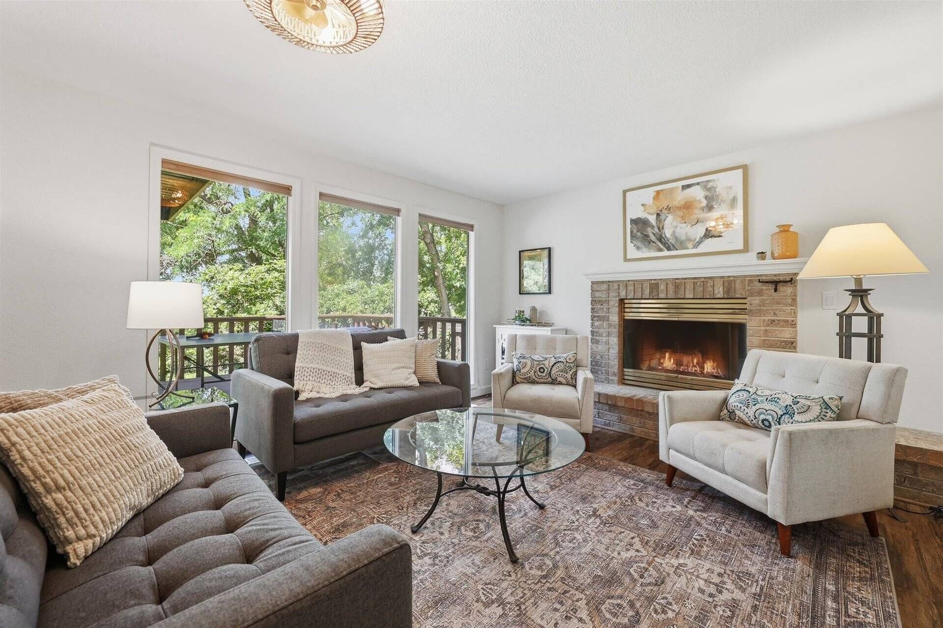 A living room with a fireplace, a glass coffee table, and a sofa.