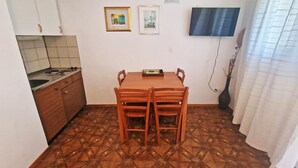 A small kitchen with a dining table and chairs, a tiled floor, and a flat-screen TV mounted on the wall. - Apartments by Seni (Kolan)