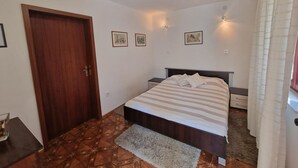 A bedroom with a bed, a wooden door, a small table, and a rug. - Apartments by Seni (Kolan)