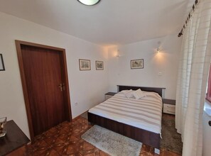 Ein Schlafzimmer mit einem Bett, einer Holztür, einem kleinen Tisch und einem Teppich.