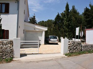 Una casa moderna de dos pisos amb un garatge, un mur de pedra i un cotxe a la zona d'entrada.