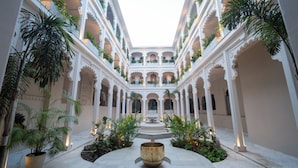 Un patio con varios niveles de balcones, plantas en macetas y una fuente central.