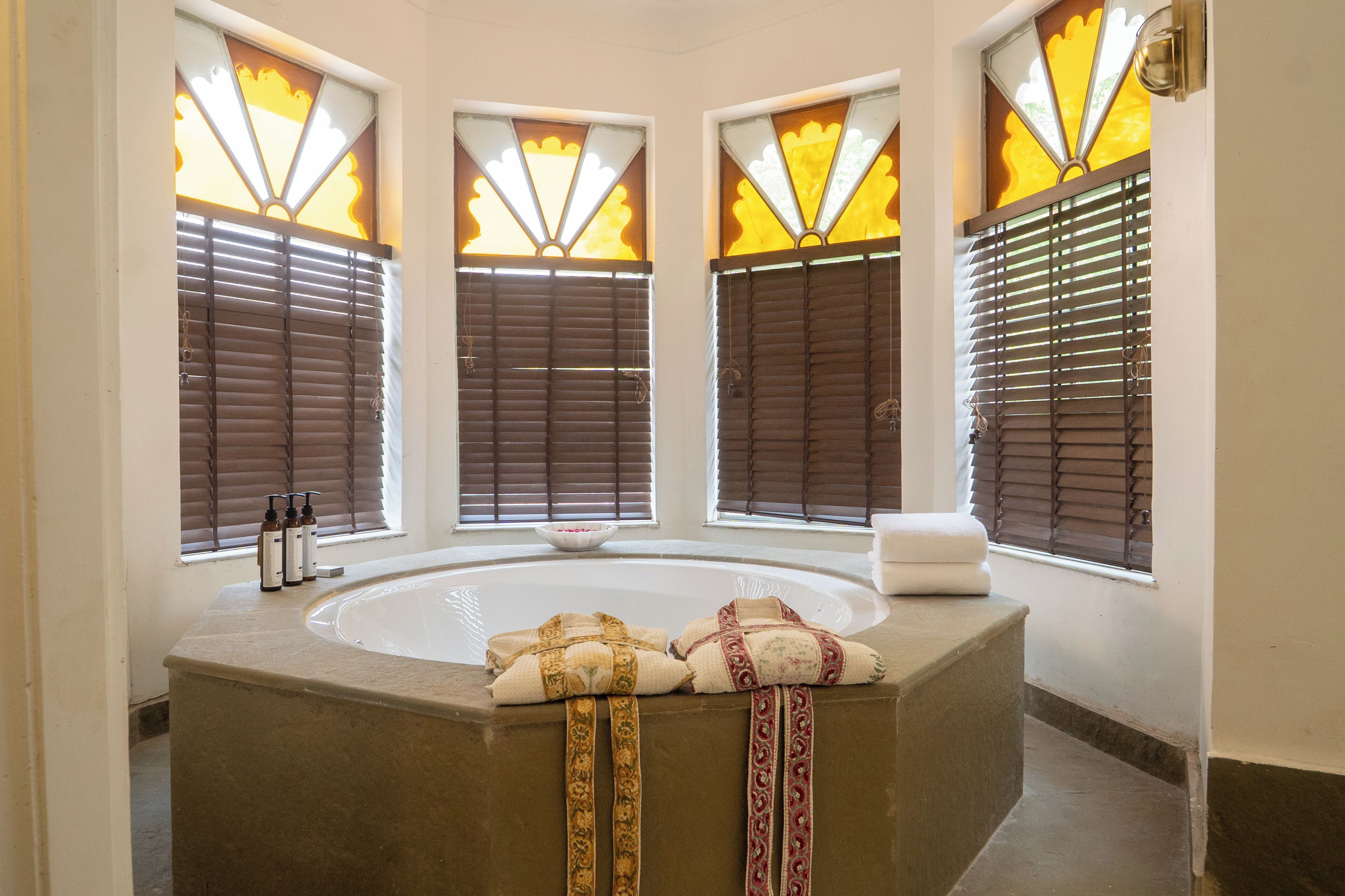 Un baño con una bañera independiente, ventanas con vidrio esmerilado y un perchero para toallas.