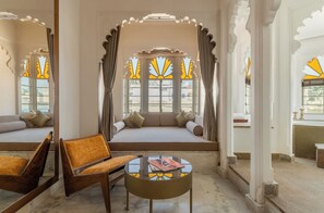 Habitación con zona de estar, una mesa y vistas a través de una ventana con vidriera decorativa.
