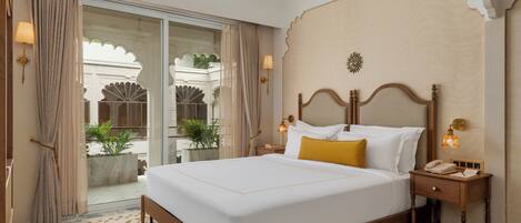 A hotel room with a large bed, a wooden headboard, a nightstand, a telephone, and a wall-mounted lamp.