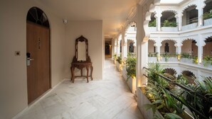 A corridor with a wooden door, a mirror, and potted plants.